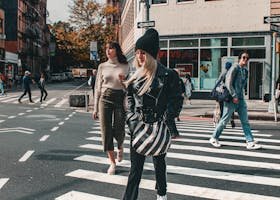 People crossing a busy street in a vibrant city setting during the day.